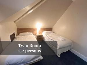 two beds in a attic room with a lamp on a table at Helen's Hotel in London