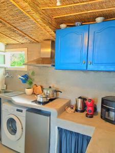 a kitchen with blue cabinets and a washing machine at Aegean Serenity - Sea View Retreat in Archangelos