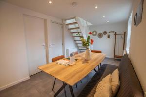 a dining room with a wooden table and a couch at De Vlindertuin in Nes