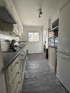 een keuken met witte kasten en een houten vloer bij T3 De Charme - avec clim, parking et piscine in Le Lavandou