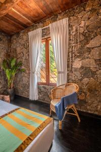a bedroom with a bed and a chair and a window at Jml villa foresta in Kalawana