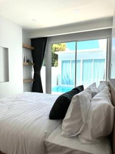 a bedroom with a large white bed with a large window at Tarn’s pool villa Rawai in Ban Saiyuan (1)