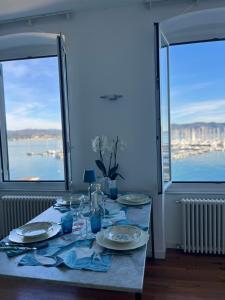 una mesa con platos y vasos con dos ventanas en About Italy Holiday Rooms and Apartments, en Portovenere