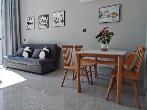 a living room with a couch and a table and chairs at Panda ZuoKe Besucher Apartment 熊猫坐客民宿 in Kunming