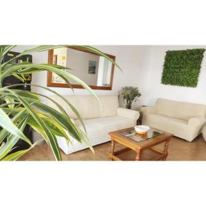 uma sala de estar com dois sofás brancos e uma mesa em Pension Villa ** em Comillas