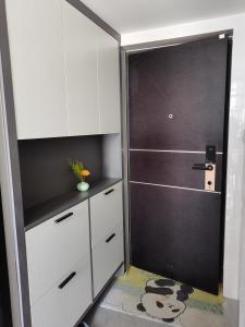 a kitchen with white cabinets and a black door at Panda ZuoKe Besucher Apartment 熊猫坐客民宿 in Kunming