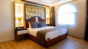 a bedroom with a bed with a large headboard at Can Adalya Palace Hotel in Antalya