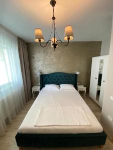 a bedroom with a large bed with a chandelier at Iris Luxury Apartaments in Mamaia +3 photos