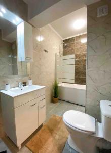 a bathroom with a toilet and a sink and a tub at Iris Luxury Apartaments in Mamaia