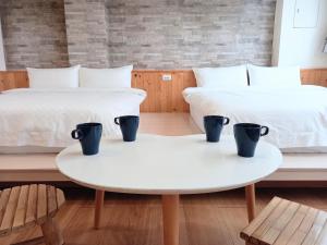 two beds with coffee cups on tables in a room at Mixa Hostel in Hualien City