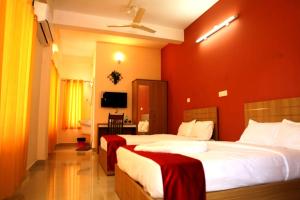 Habitación de hotel con 2 camas y paredes rojas en Karamangattu Residency, en Ramakkalmedu