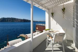 a balcony with a table and chairs overlooking the water at Lava Stone in Oia
