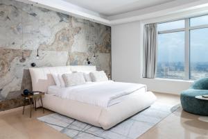 a white bedroom with a white bed and a stone wall at BreezHouse P 61 in Ramat Gan