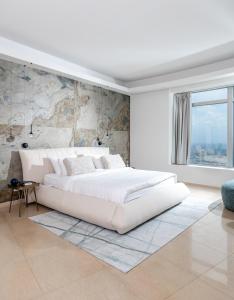 a white bedroom with a large white bed and a wall at BreezHouse P 61 in Ramat Gan