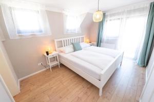 1 Schlafzimmer mit einem weißen Bett und 2 Fenstern in der Unterkunft Landhaus Appartements Gretl by S4Y in Krumpendorf am Wörthersee