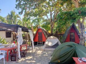 a group of tents and tables in the sand under trees at SHALOM CAMP in El Nido