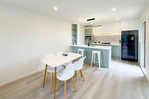 a kitchen with a table and chairs and a refrigerator at Brand New 3-Bedroom Townhouse in Albany in Auckland