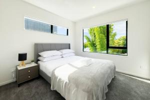 Habitación blanca con cama y ventana en Brand New 3-Bedroom Townhouse in Albany en Auckland