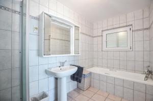 a white bathroom with a sink and a bath tub at Swept Away B&B - No-Loadshedding in Yzerfontein