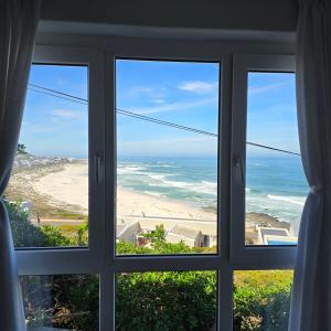 a window with a view of a beach and the ocean at Swept Away Guesthouse - No-Loadshedding in Yzerfontein