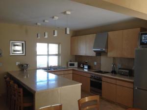 a kitchen with wooden cabinets and a counter top at Calypso Beach Holiday House in Langebaan