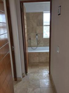 a bathroom with a tub and a shower with a window at Calypso Beach Holiday House in Langebaan