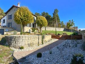 um jardim com uma parede de pedra e uma casa em Chez Niréas & Serge em Blavozy