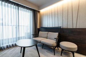 a room with two chairs and a table and a window at Kyohotel Kishotei Goshominami in Kyoto