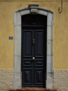 uma porta preta num edifício com uma parede de pedra em Grande maison de vacances em Saint-Laurent-de-la-Salanque