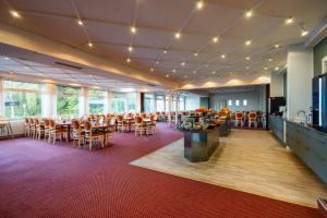 a restaurant with tables and chairs in a room with windows at Milling Hotel Søpark in Maribo