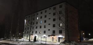 um grande edifício branco na neve à noite em Tilava huoneisto em Lahti