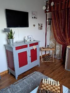 Aux Volets Bleus في Sibiril: غرفة معيشة مع تلفزيون وطاولة شطرنج