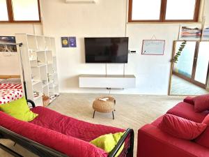 uma sala de estar com dois sofás vermelhos e uma televisão em B&B The Loft em Gioiosa Ionica