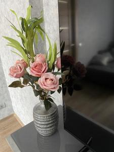 um vaso com rosas cor-de-rosa numa mesa ao lado de um espelho em Dzīvoklis centrā em Jēkabpils