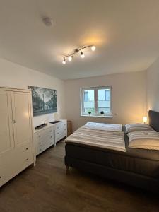 a bedroom with a bed and a dresser and two windows at TOP-Ferienwohnung bei Berlin, bis 3 Gäste, Terrasse und Garten in Bestensee