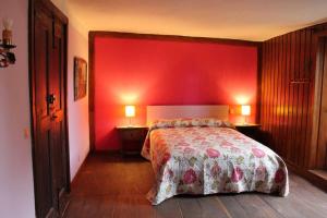 una camera da letto con una parete rossa, un letto e 2 lampade di Kukuma Etxea Habitaciones con derecho a cocina a Galarreta