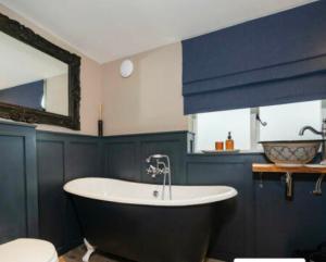 y baño con bañera y paredes azules. en Little Mouse Cottage, en Lavenham