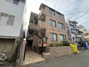 Naka-tomiにあるAkazu-hostel newのレンガ造りの建物で、自転車がその前に駐車されています。