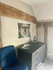 a bedroom with a blue chair and a dresser at Little Mouse Cottage in Lavenham