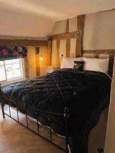 um quarto com uma grande cama preta num quarto em Little Mouse Cottage em Lavenham