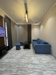 uma sala de estar com um sofá azul e uma televisão em New apartment in Yunusobod dist. em Tashkent