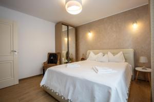 a bedroom with a white bed with two towels on it at Perfect Apartment Central in Braşov