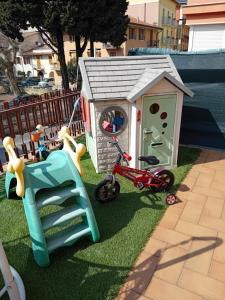 ein kleiner Kinderspielplatz mit einem Spielzeughaus und einem Fahrrad in der Unterkunft Garda City Home Family Apartments in Garda