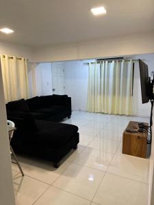 a living room with a black couch and a tv at Home Away Comfort stay in Suva
