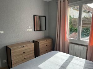 1 dormitorio con cama, espejo y ventana en La maison du chêne, en Chaignay