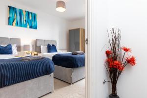 a bedroom with two beds and a vase with red flowers at Stevenage - 2 Bedroom Apartment, Free Wifi & Balcony Upto 5 guests in Stevenage