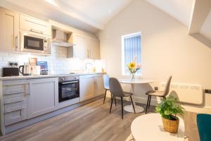 a kitchen with white cabinets and a table and chairs at MSRSH lux 5 in Manchester