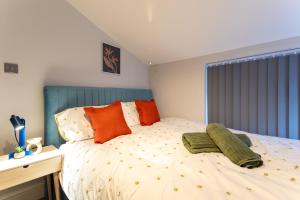 ein Schlafzimmer mit einem Bett mit orangefarbenen und grünen Kissen in der Unterkunft MSRSH lux 5 in Manchester