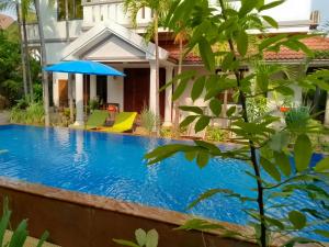 una piscina frente a una casa con sombrilla en Passport Villa, en Siem Reap