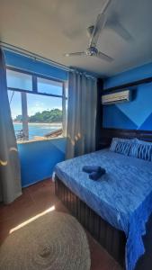 a bedroom with a blue bed with a large window at Hostel Recanto da Sereia in Salvador